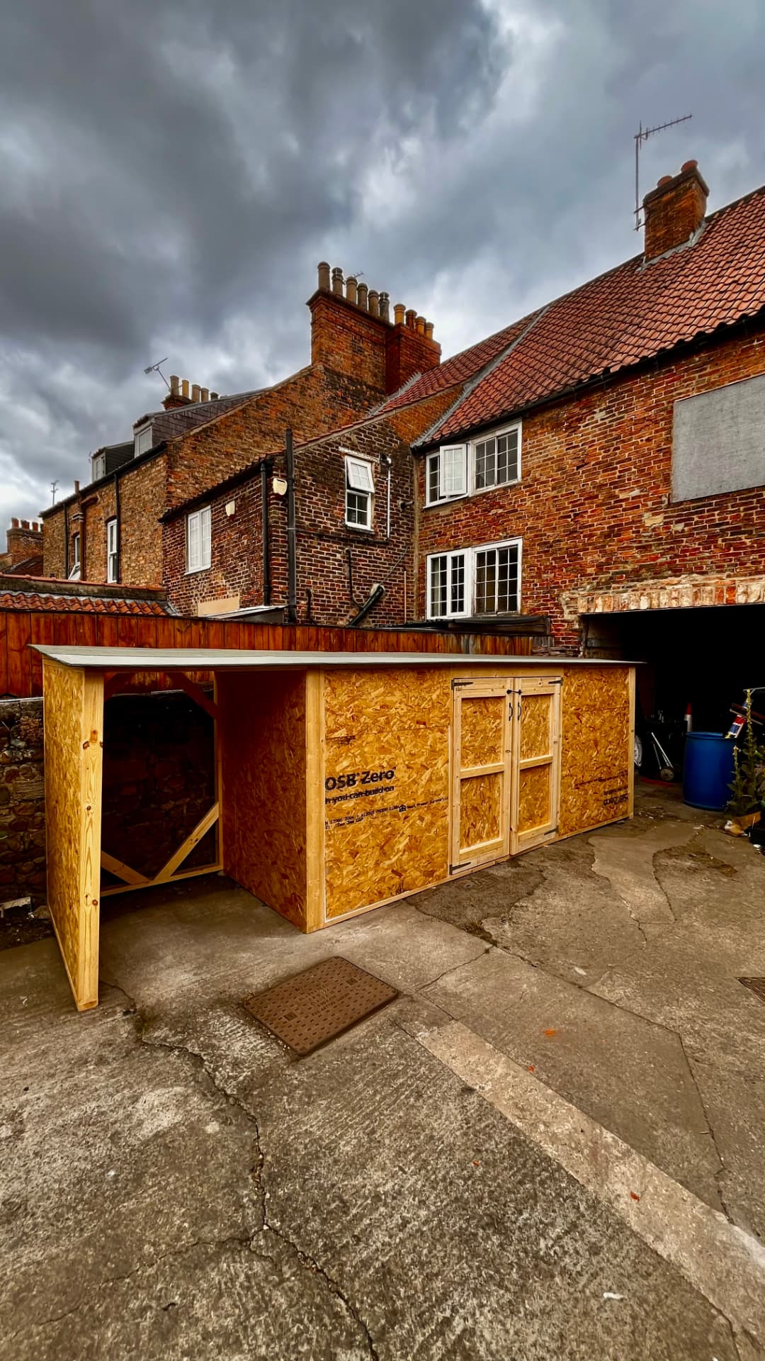 Custom-built timber storage unit with doors in a brick courtyard